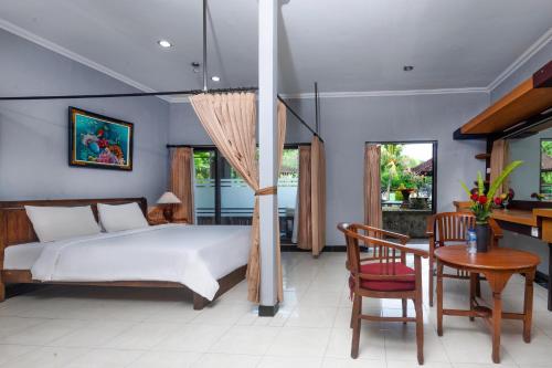 1 dormitorio con 1 cama, mesa y sillas en Dewi Sinta Hotel and Restaurant, en Tanah Lot