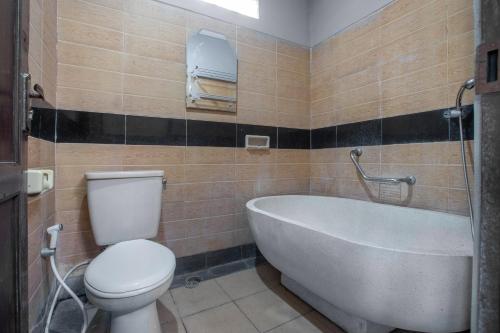 a bathroom with a tub and a toilet and a sink at Dewi Sinta Hotel and Restaurant in Tanah Lot