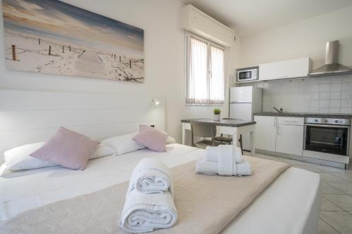 a bedroom with a large white bed with towels on it at Rimini Bay Suites&Residence in Rimini