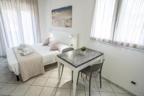 a bedroom with a bed and a table and a table and chairs at Rimini Bay Suites&Residence in Rimini