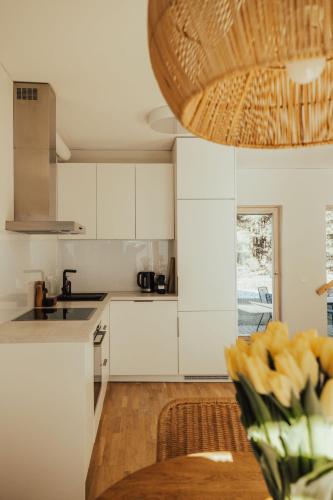 a kitchen with white cabinets and a table with flowers at House 100 m to the sea in Monciske, free parking in Monciškės