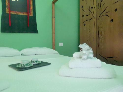 a bed with a tray of towels and two cups on it at Speciale Tarshito Guesthouse Bari in Bari