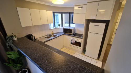 a kitchen with white cabinets and a black counter top at 2BR 2Bath L4 Executive Apartment, in City Centre in Canberra