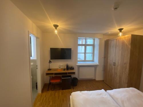 Schlafzimmer mit einem Bett und einem Schreibtisch mit einem TV in der Unterkunft Altstadthotel Alt & Jung in Regensburg