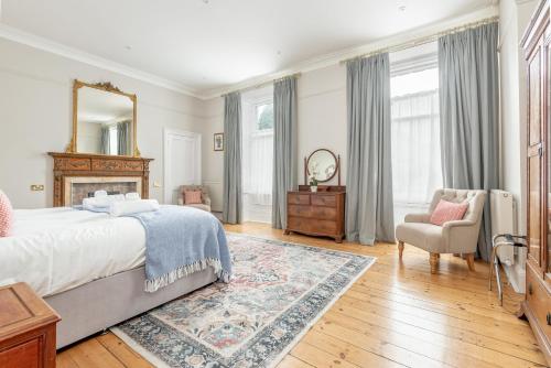 a bedroom with a bed and a mirror and a chair at Greyfriars Bothy - Luxury Central 2 Bed Apartment in St. Andrews