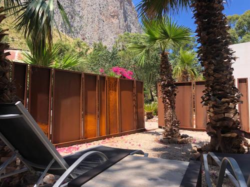 a yard with a fence and a chair and palm trees at Araja Villa&Suite by Geocharme in San Vito lo Capo