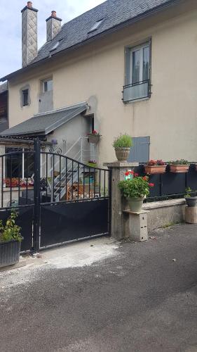 une maison avec un portail noir et quelques plantes en pot dans l'établissement la maison des fleurs studio, à Le Mont-Dore