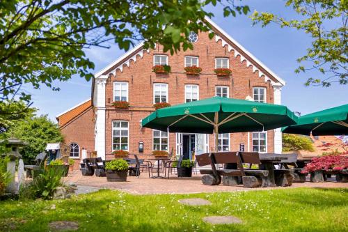 a building with a picnic table and a green umbrella at Hotel Landhaus Steinfeld in Greetsiel