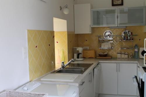 a kitchen with white cabinets and a sink at La Maison de Lésa in Poullan-sur-Mer