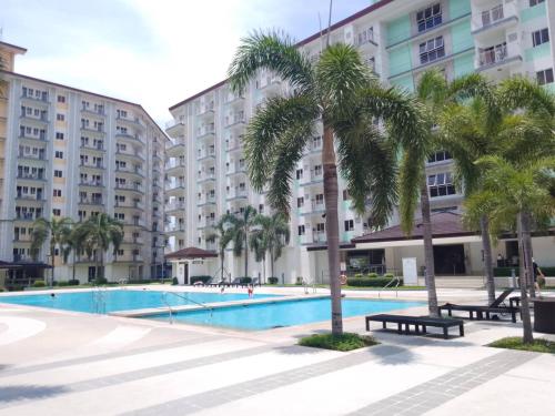 a swimming pool with palm trees and buildings at Paranaque SM-Sucat Field Res. Bldg 5, 2/F, 2BR with Balcony in Manila