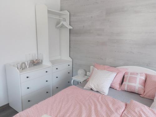 a bedroom with a pink and white bed and a dresser at APARTMENT WITH A VIEW in Bohinjska Bistrica