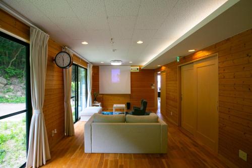 a living room with a couch and a clock at 佐世保VILLA青鹿Ur1 in Sasebo