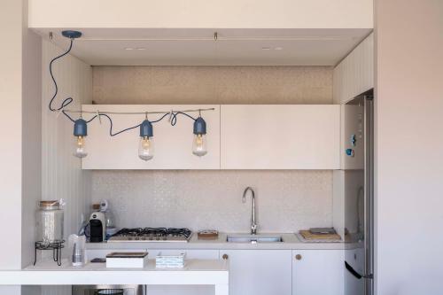 a kitchen with white cabinets and a sink and lights at San Vito Luxury Accomodation in Polignano a Mare