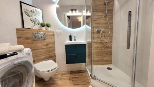 a bathroom with a toilet and a shower and a washing machine at Apartament Arkadia Augustow in Augustów