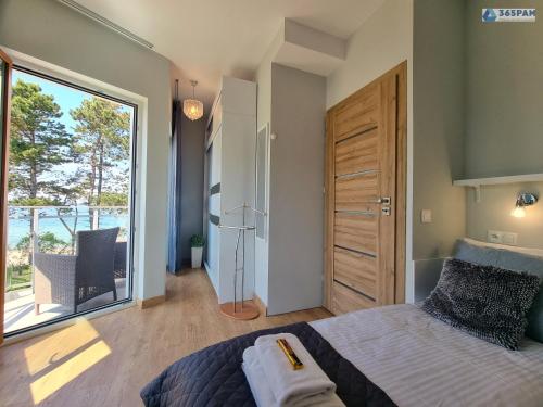um quarto com uma cama e uma grande janela em Apartament LET'S SEA z widokiem na morze - 365PAM em Gąski