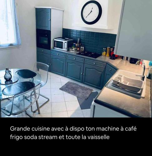 une cuisine avec une table et une horloge au mur dans l'établissement Belle villa à 5 mn du centre avec grd jaccuzy, à Montpellier