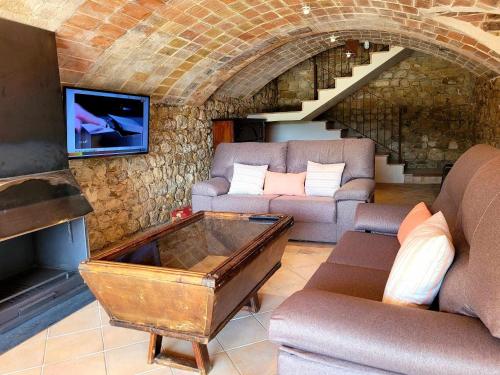 a living room with a couch and a tv on a brick wall at Recientemente restaurada, ideal para grupos! in Cabanellas