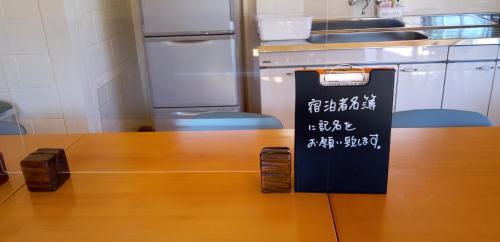 a table in a kitchen with a sign on it at ペンション村山里 in Yamazatu