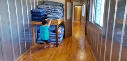 a young boy playing in a room with beds at ペンション村山里 in Yamazatu