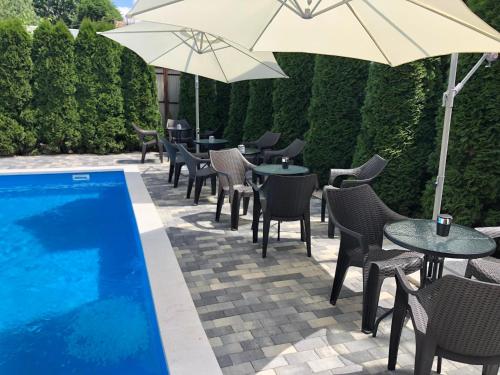 a patio with tables and umbrellas next to a swimming pool at Hotel Brill Orosháza in Orosháza