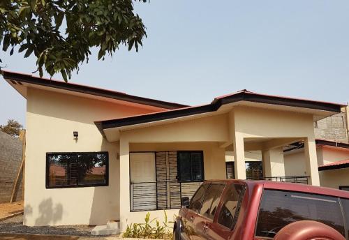a small house with a red car parked in front of it at Portersville Private Lodge in Freetown