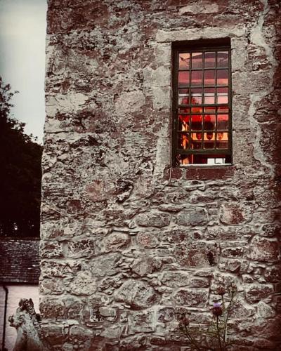 a window of an old stone building with red candles at Buittle Castle Exclusive Use- Stay in your own Castle! in Castle Douglas