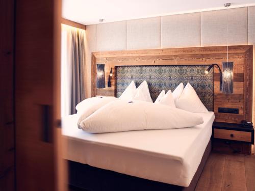 a bed with white sheets and pillows in a room at Platzlhof - Mein Hotel im Zillertal in Ried im Zillertal