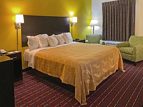 um quarto de hotel com uma cama e uma cadeira em Quality Inn Henderson I-85 em Henderson