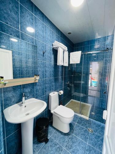 a blue tiled bathroom with a toilet and a sink at Calligraphy Hotel and Cottages in Mtsvane Kontskhi