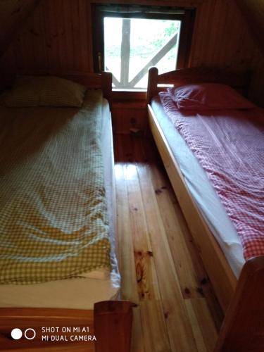 2 camas individuales en una habitación con ventana en Domek letniskowy-Powidz ul.Topolowa en Powidz