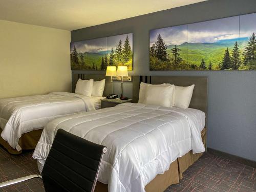 a hotel room with two beds and paintings on the wall at Clarion Pointe - Greensboro Coliseum Area in Greensboro