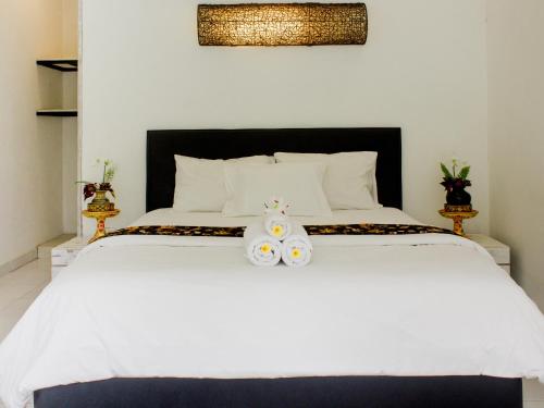 a bedroom with a white bed with two flowers on it at The Winaposa in Munduk