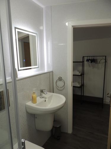 a white bathroom with a sink and a mirror at Braeview Studio in Macduff
