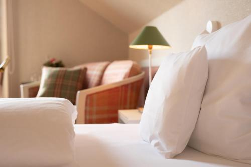 a bedroom with a bed with white pillows and a chair at Hotel Restaurant Krone in Hayna