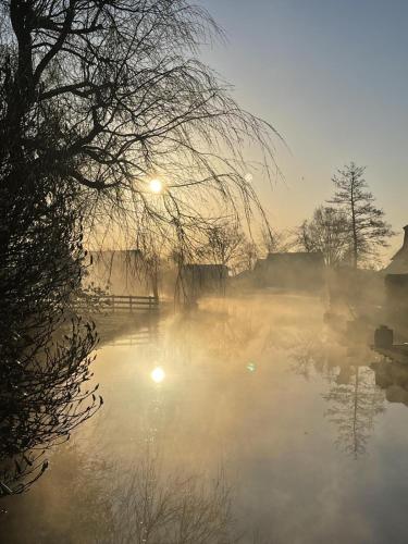 a misty river with the sun rising in the background at B&B De Meije in Nieuwkoop