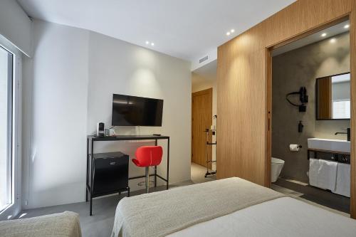 ein Schlafzimmer mit einem Bett und einem roten Stuhl in der Unterkunft Ella Hostel Ramblas in Barcelona