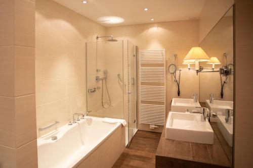 a bathroom with two sinks and a tub and a shower at Hotel Restaurant Krone in Hayna