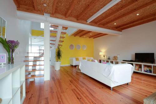 a living room with white furniture and yellow walls at CASASUPERTUBOS - Villa 9 in Peniche