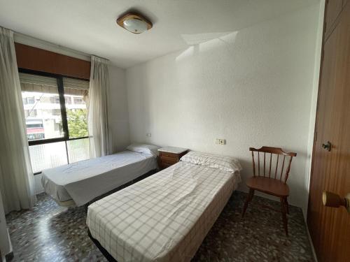 una habitación de hotel con 2 camas y una silla en PV20A, Gran apartamento en el centro con vistas al mar, en Villajoyosa