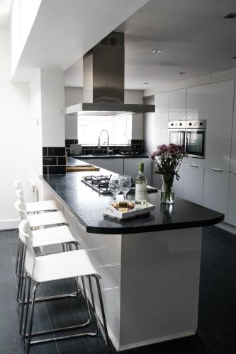 a kitchen with a black counter and white cabinets at Gorgeous 3 Bedroom Victorian Townhouse in Lisburn
