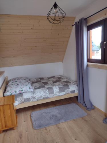 a bed in the corner of a room with a window at Góralski Domek Tomek in Ciche