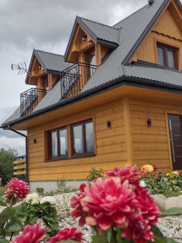 a wooden house with flowers in front of it at Góralski Domek Tomek in Ciche