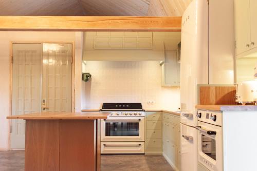 La cuisine est équipée de placards blancs et d'un four avec plaques de cuisson. dans l'établissement Pinewood Guesthouse, à Mäntsälä