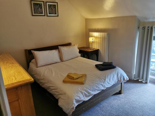 a bedroom with a bed with two towels on it at Clover Cottage in Winster