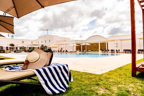 a person sitting on a chair next to a swimming pool at TMK Flora Park by Turismark - Adults Only in Hammamet