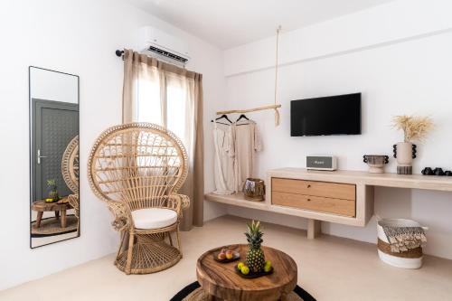 ein Wohnzimmer mit einem TV, einem Stuhl und einem Tisch in der Unterkunft PAREA Paros - Adults Only in Kampos Paros