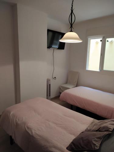 1 dormitorio con 2 camas, TV y lámpara en Precioso apartamento con garaje en Avenida Andalucía 77 playa Mezquitilla en Algarrobo