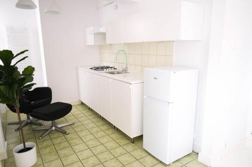 a white kitchen with a white refrigerator and a chair at Apartamenty Mrągowo Warszawska Cudo Studio in Mrągowo