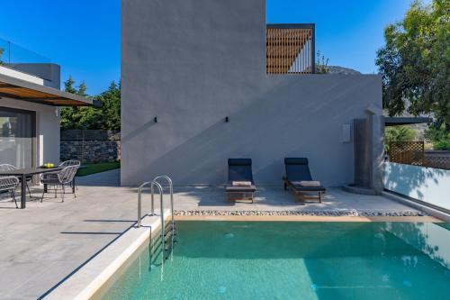 a swimming pool with two chairs next to a house at Paligremnos Residences, a Beachside Retreat, By ThinkVilla in Plakias