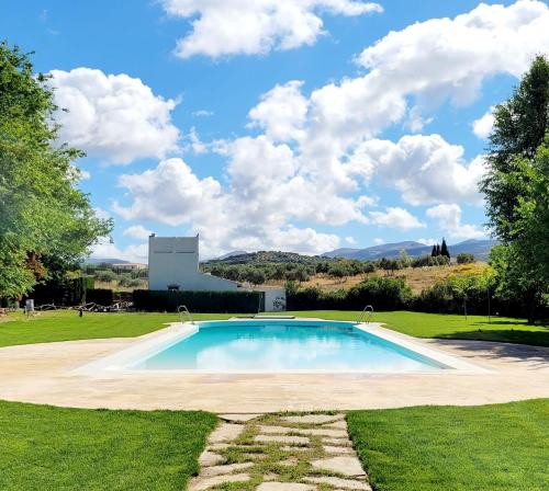 a swimming pool in the middle of a grass field at Hotel Bodega El Juncal in Ronda
